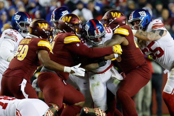 Washington Commanders defensive tackles Jonathan Allen (93) and Daron Payne (94) wrap up New York Giants running back Saquon Barkley during the third quarter at FedExField in 2022.